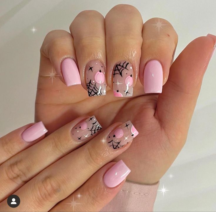 Charming Pastel Pink Nail Design with Whimsical Spiderwebs and Adorable Cartoons for Seasonal Celebrations.