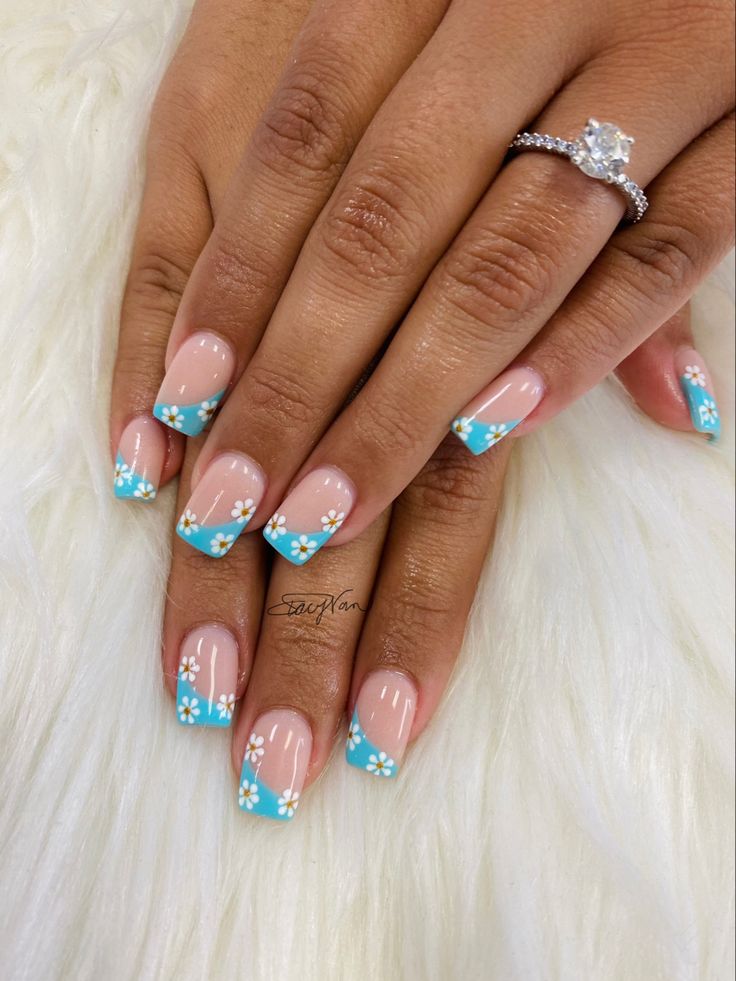 Playful Pastel Nail Design with Blue French Tips and Elegant White Floral Accents.