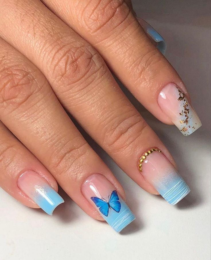 Chic Ombre Nail Design with Blue Gradients, Butterfly Art, and Elegant Gold Accents.