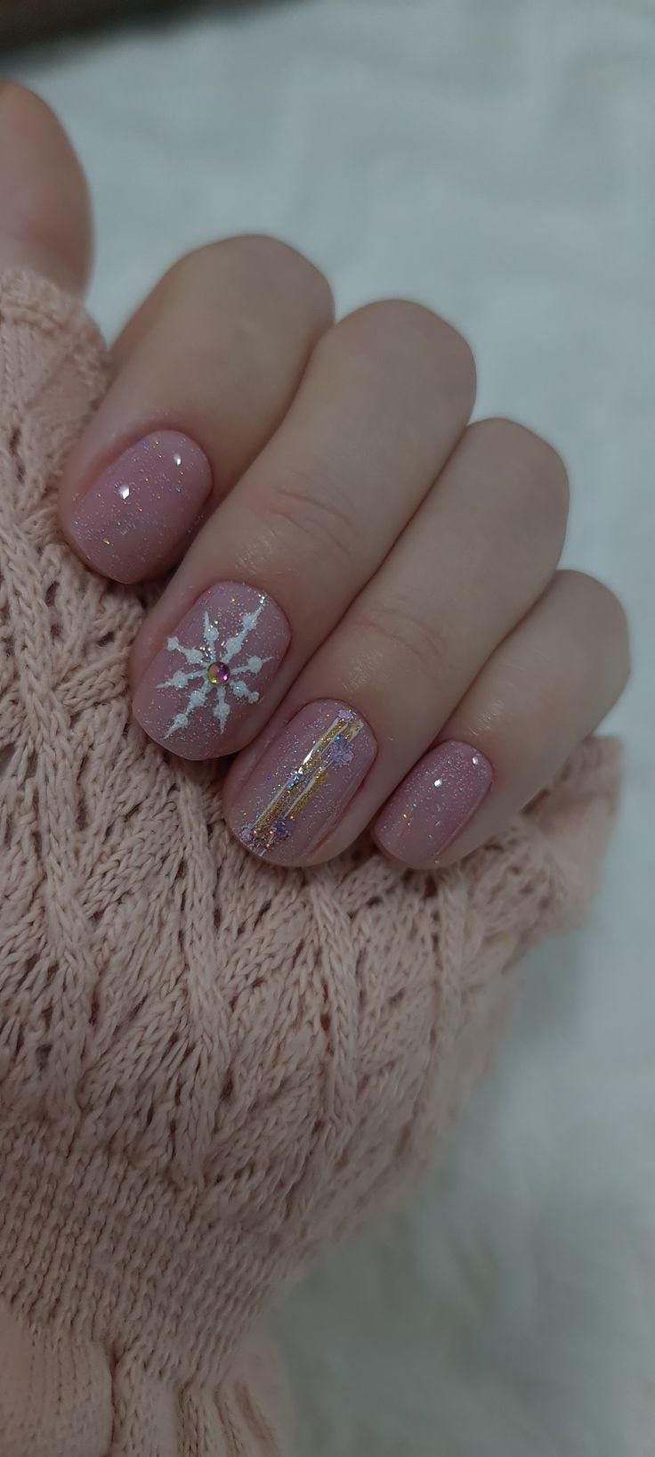 Elegant Winter Nail Design with Soft Pink Base, Shimmer, Snowflake Accent, and Gold Stripe.