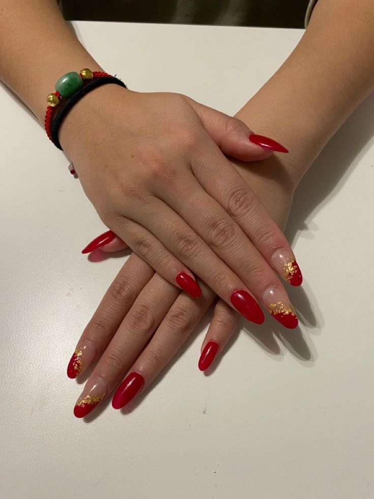 Festive Elegant Red Nail Design with Glossy Tips and Glittery Gold Accents.