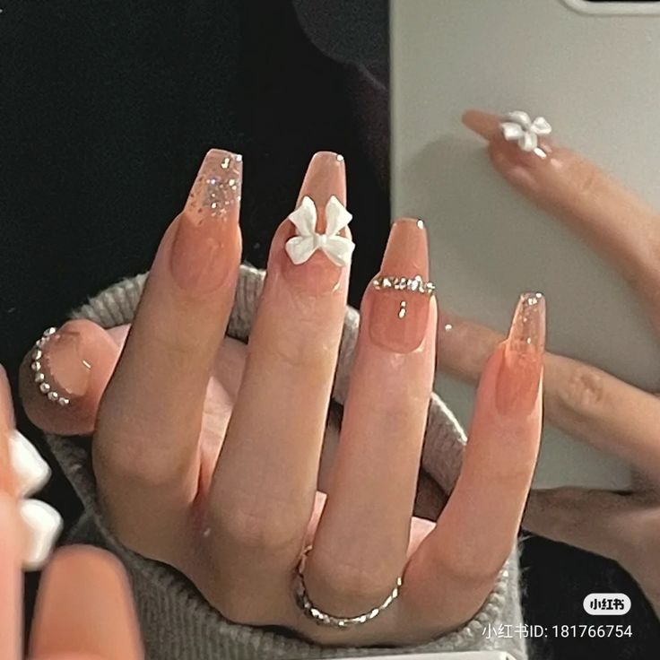 Sophisticated Nail Art: Soft Nude Base with Shimmering Accents and 3D Floral Detail.