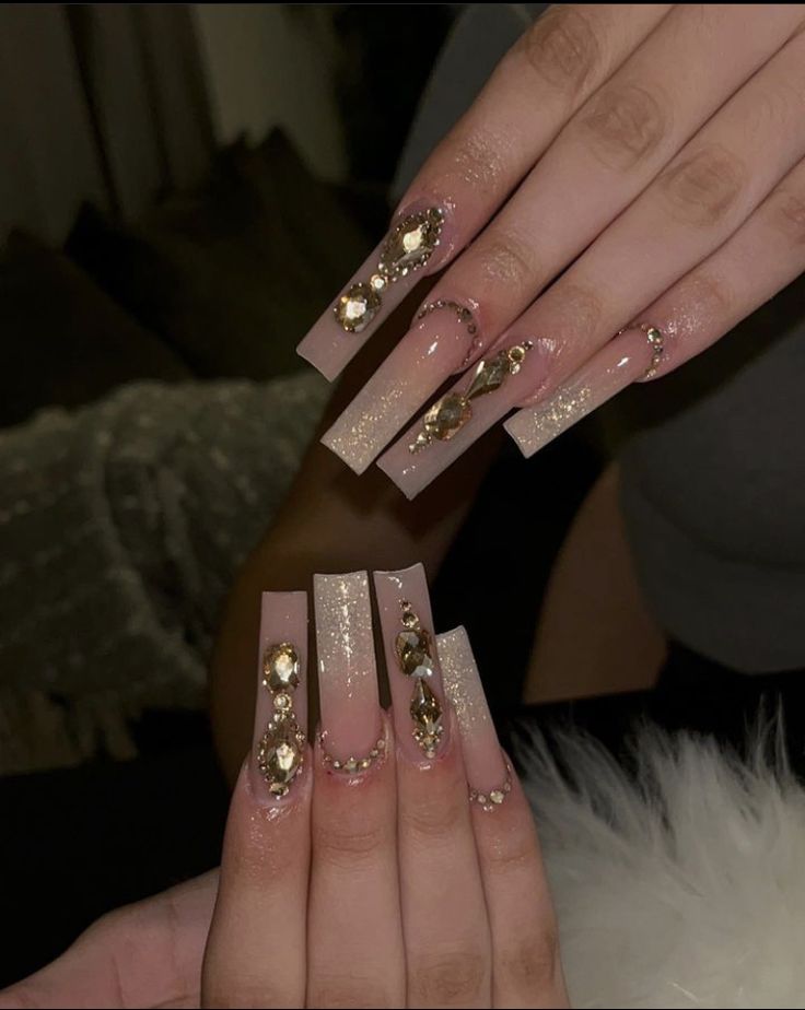 Glamorous Jewel-Embellished Long Acrylic Nails with Sparkling Glitter on a Nude Base.