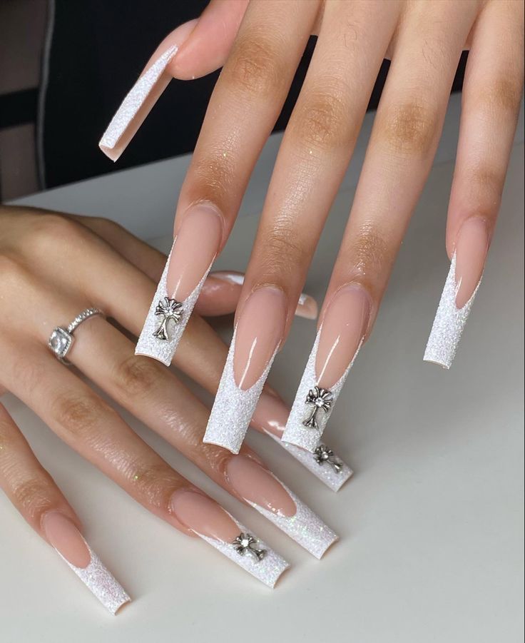 Chic Long Square Nail Design with Soft Nude Base, Sparkling Glitter Accents, and Sophisticated Silver Charms.