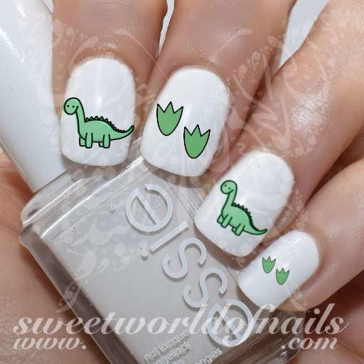 Whimsical Nail Art: White Polish with Adorable Green Dinosaurs and Leaf Motifs