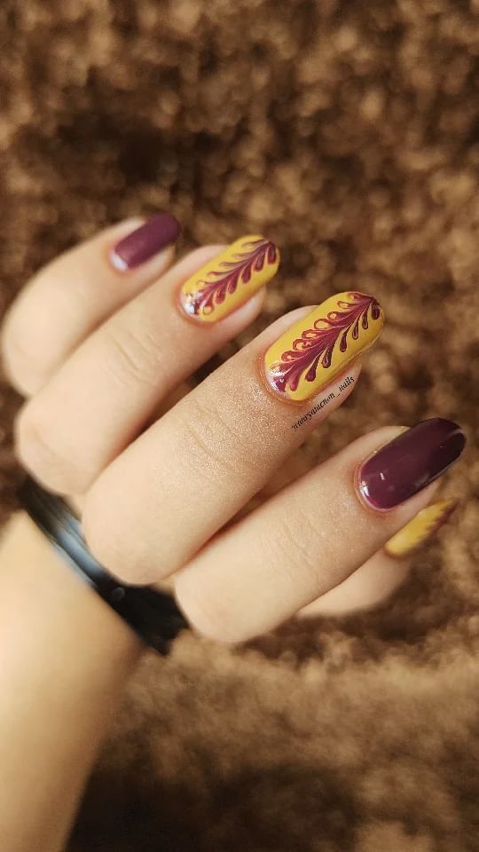 Vibrant Nail Design: Bold Purple and Yellow Base with Intricate Floral Patterns in Rich Red and Orange.