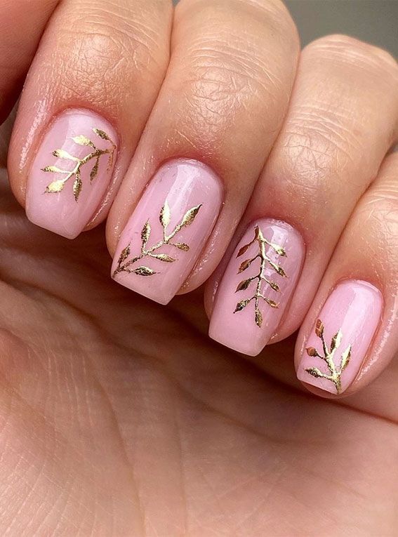 Elegant Soft Pink Nail Art with Gold Leaf Accents for a Modern Touch.