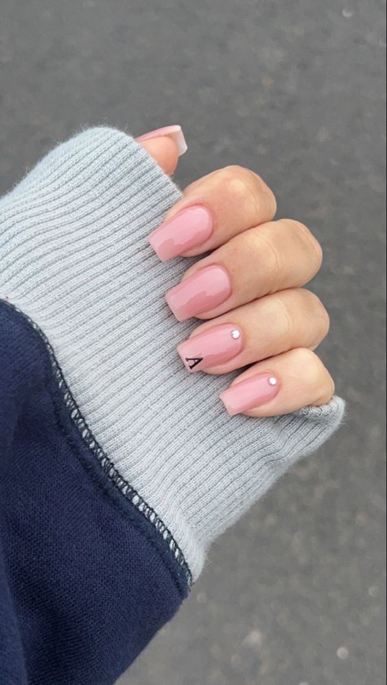 Chic Glossy Pink Square Nails with Subtle Gemstone and Letter Accents.