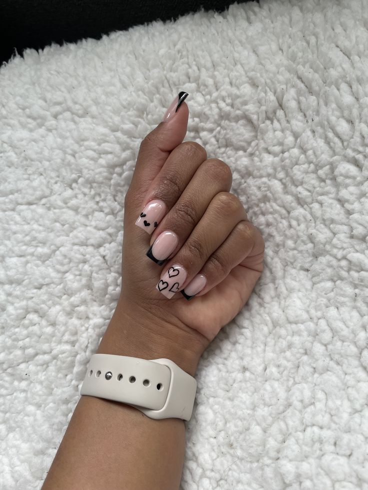 Elegant Nude Base Nail Design with Delicate Black Hearts and Contrasting Tips.