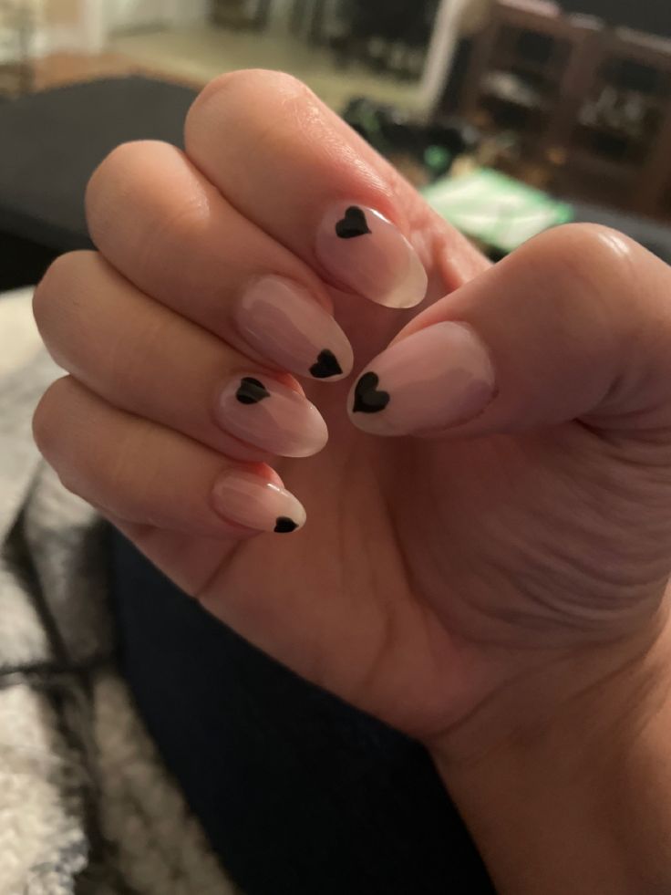 Elegant French Tip Nail Design with Pale Pink Polish and Black Heart Accents.