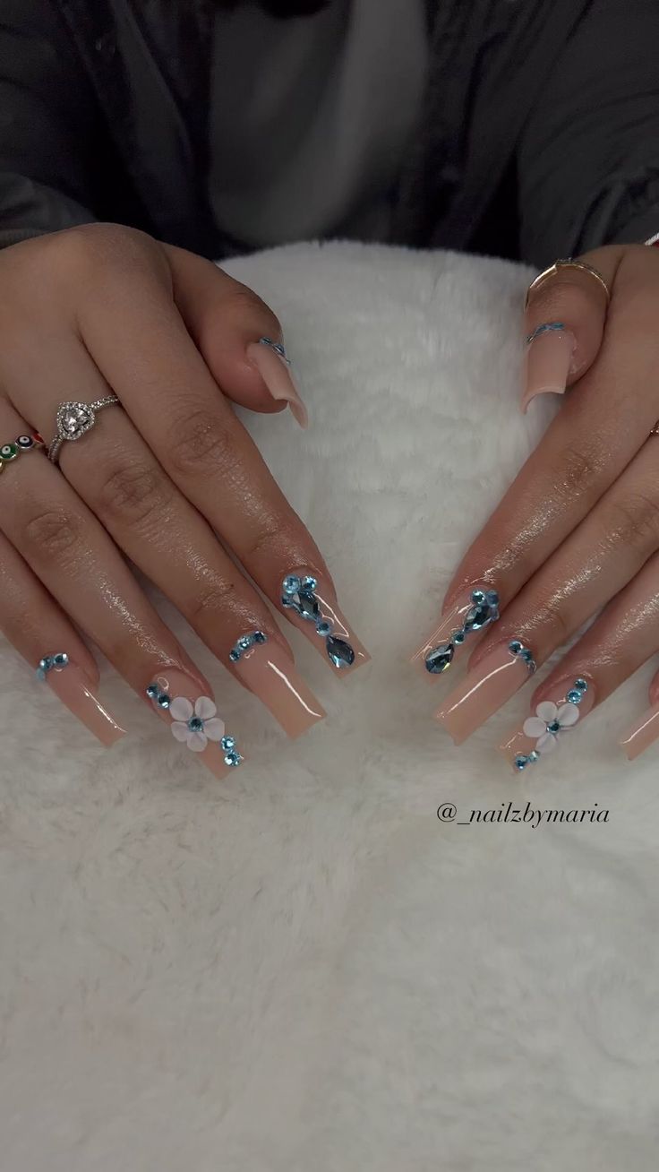 Elegant Floral Nude Nail Design with Vibrant Blue Embellishments.