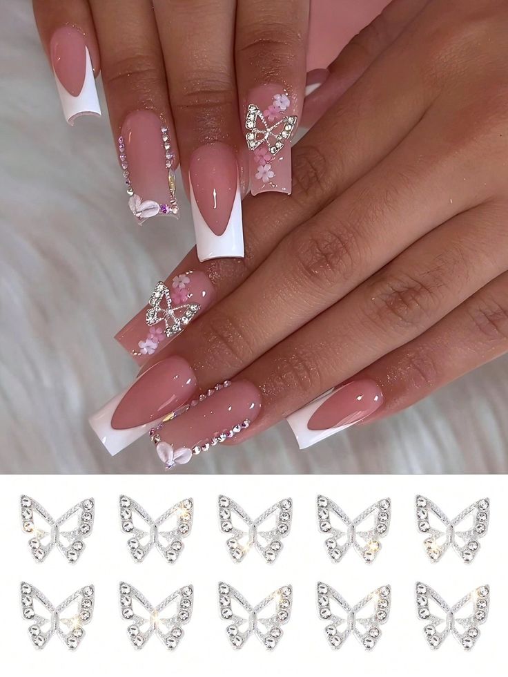 Chic Pink and White Floral Nail Design with Rhinestones and Butterfly Charms.