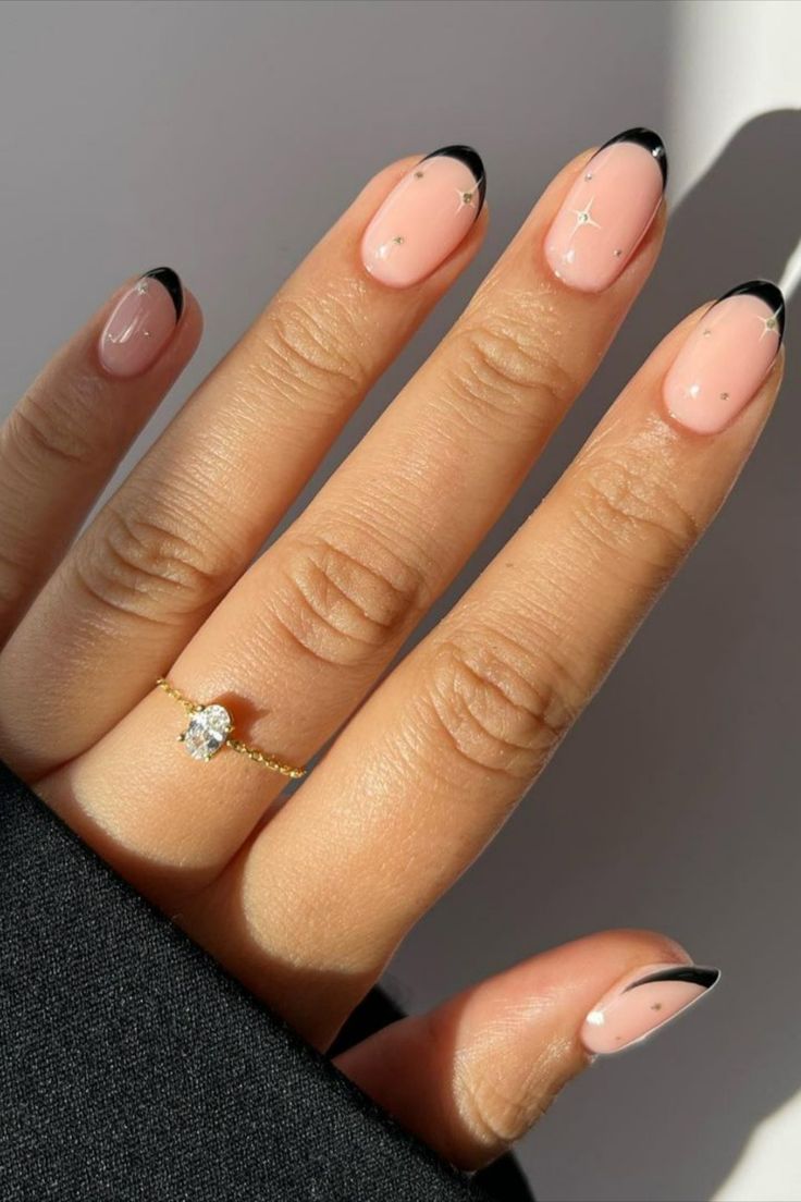 Chic Soft Pink and Black Nail Design with Sparkling Star Accents.