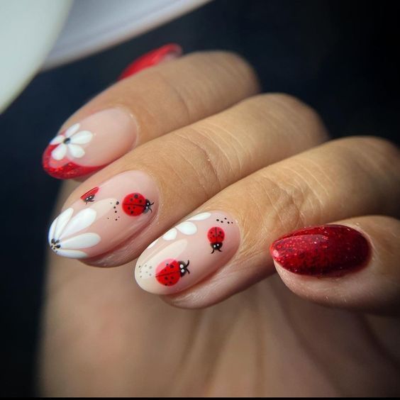 Whimsical Spring Nail Design with Red and White Accents, Ladybug Motifs, and Sparkling Tips.