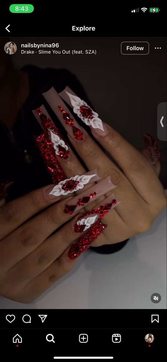 Glamorous Long Nail Design with Red Gemstones and White Floral Accents.