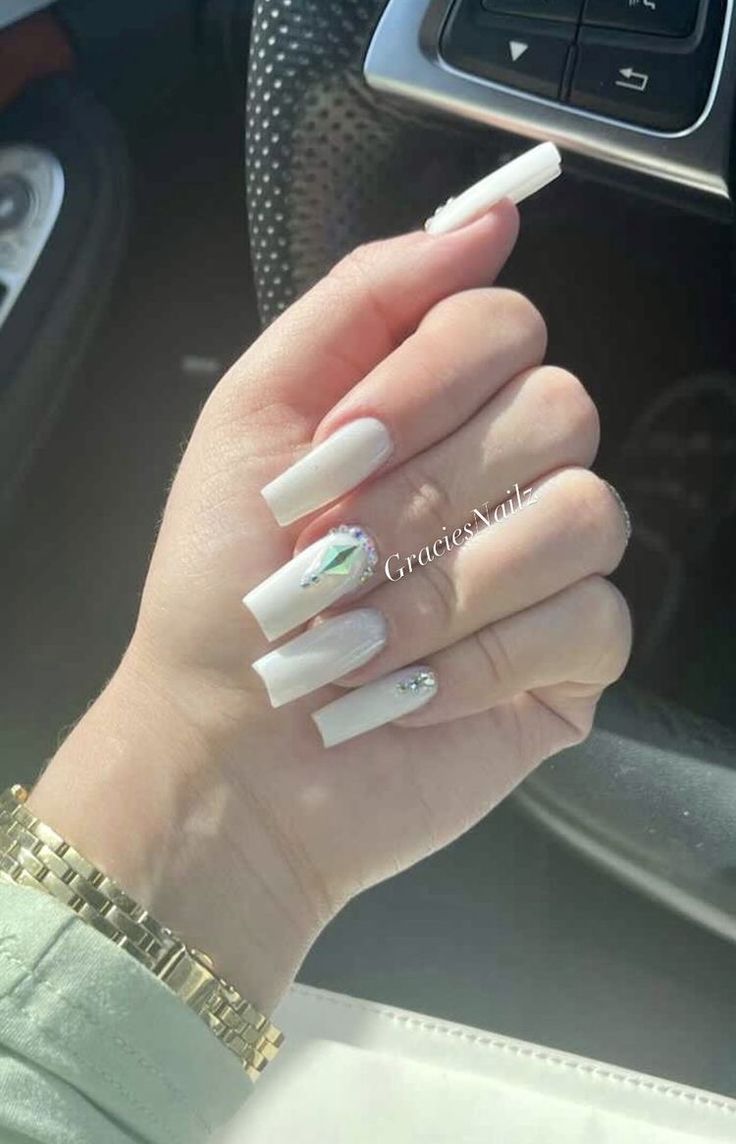 Sophisticated Long Nails with Pristine White Polish and Glamorous Gem Accents.