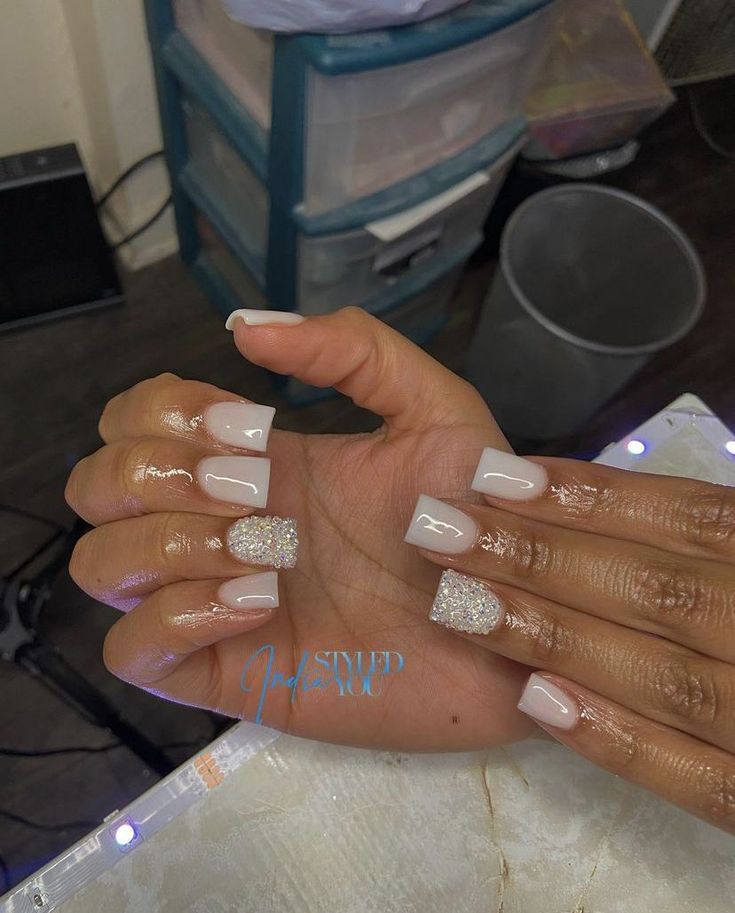 Sophisticated Nail Design: Chic Nude with Sparkling Glitter Accent.