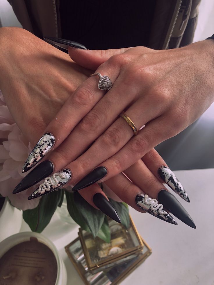 Sophisticated Elegant Dark Stiletto Nail Design with Marble Patterns and Glamorous Accents.