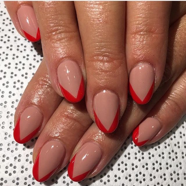 Chic Almond-Shaped Nails: Nude Base with Bold Red Chevron Tips for a Stylish Statement.