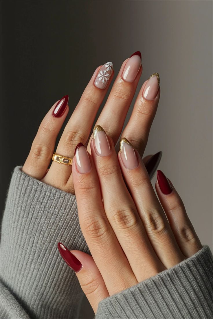 Chic Winter Nail Design: Sophisticated Deep Red and Nude with Glamorous Gold Accents and Snowflake Motif