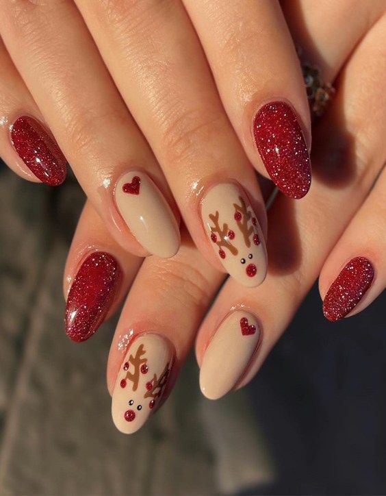 Cheerful Holiday Nail Design: Nude Base with Glittering Red Tips and Playful Reindeer Embellishments.