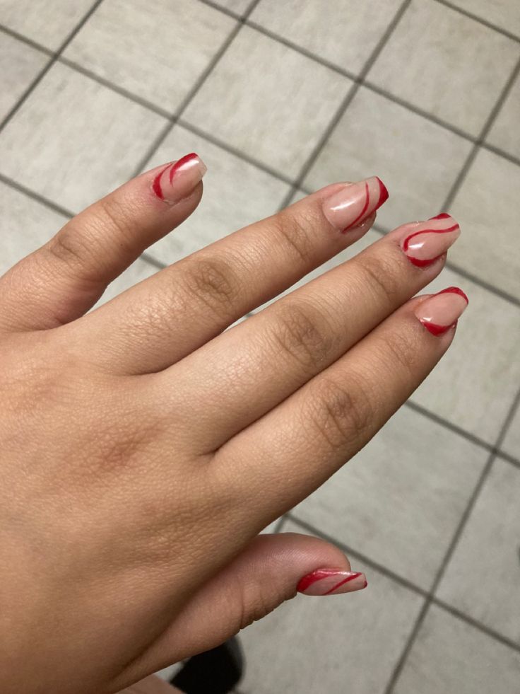 Chic Nail Design with Playful Swirls in Soft Pink and Vibrant Red Accents.