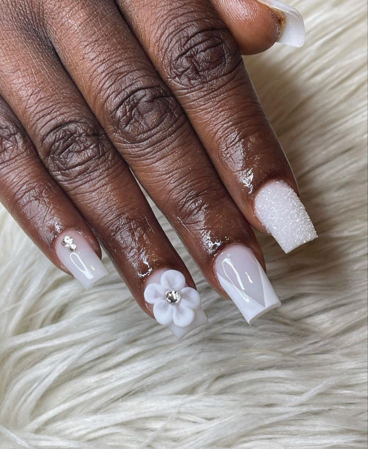 Chic White Nail Design with Textured Finishes and Gem-Adorned 3D Flower.