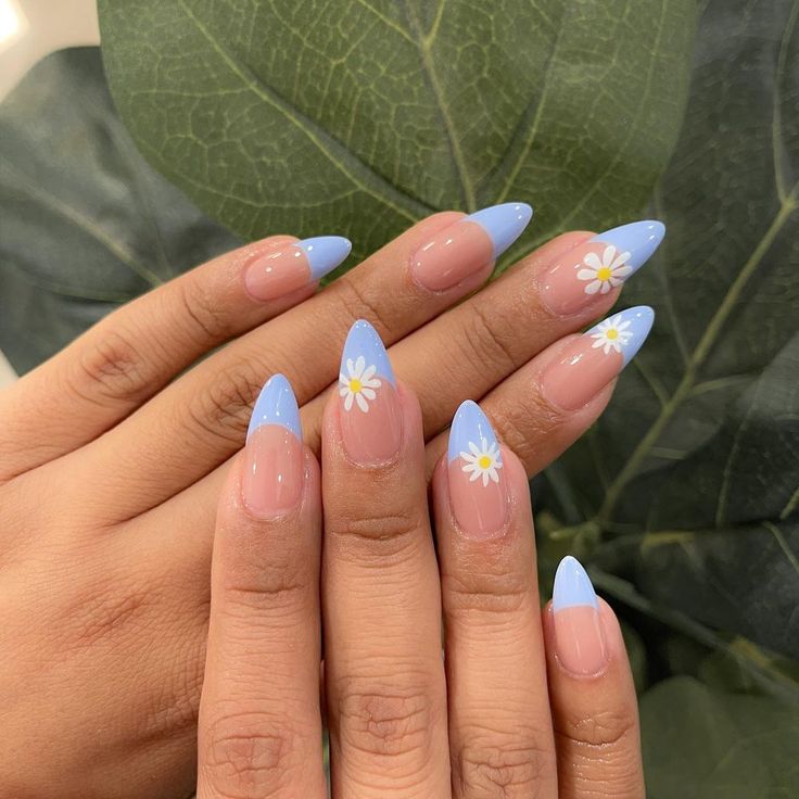 Chic Almond-Shaped Nails with Pastel Blue Tips and Whimsical Daisy Accents for a Spring-Inspired Look.