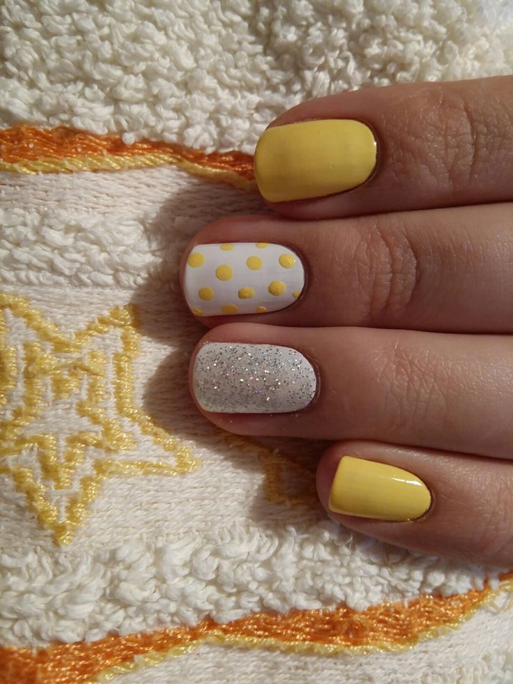 Vibrant Yellow and Pastel Nail Design with Whimsical Polka Dots and Shimmering Silver Accent.