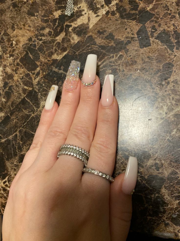 Elegant Long Nail Design: Soft White with Glittering Accents and Rhinestone Glamour.