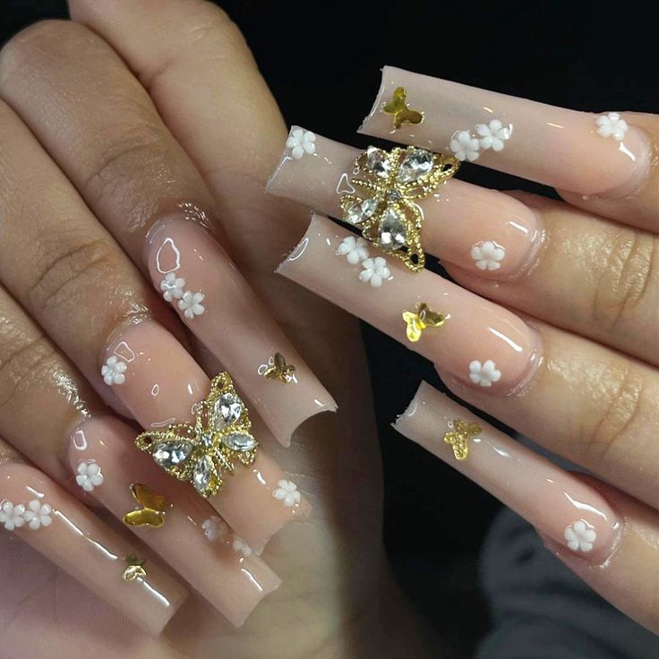 Glamorous Nail Design: Soft Nude Base with White Flowers and Gold Butterfly Accents