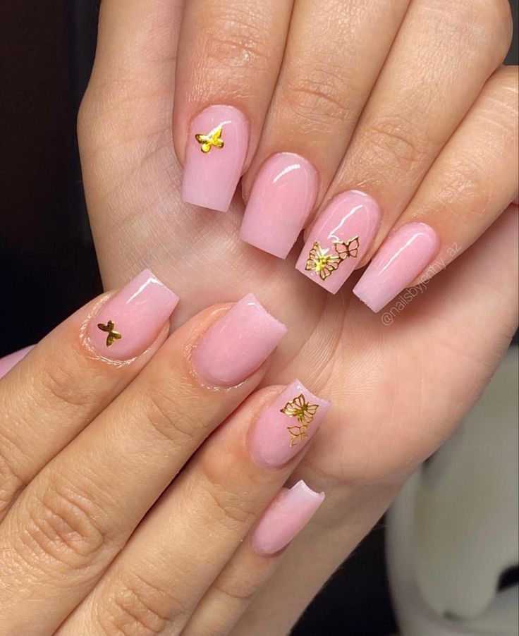 Chic Soft Pink Nails with Delicate Gold Butterfly Accents for Elegant Occasions.