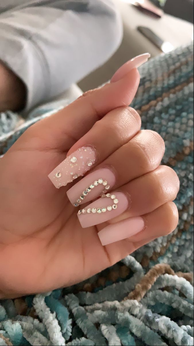 Elegant Pastel Pink Nail Design with Intricate Embellishments and Playful Heart Shape.