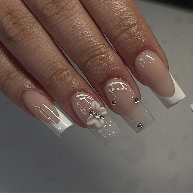 Sophisticated Nude and White Nail Design with Floral Accents and Rhinestones.