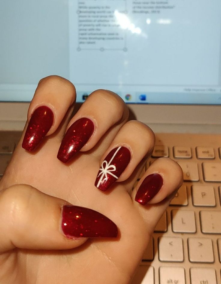 Festive Red Glitter Nails with Delicate White Design for Holiday Elegance.