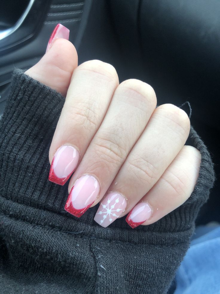 Chic Winter Nail Design: Soft Pink Base with Bold Red Tips and Festive Snowflake Accent.