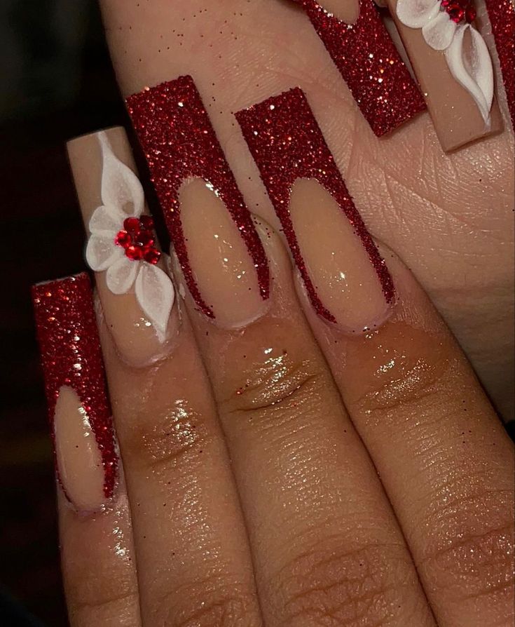 Elegant Glittery Red and Nude Nail Design with Festive Floral Accents.