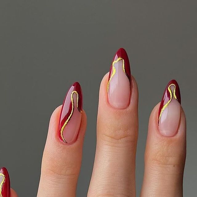 Chic Deep Red Stiletto Nails with Golden Accents for Elegant Occasions.