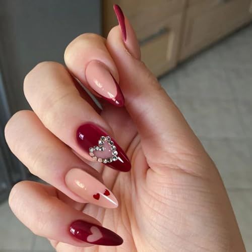 Romantic Nail Design: Deep Red and Nude Shades with Heart Motifs and Rhinestones.