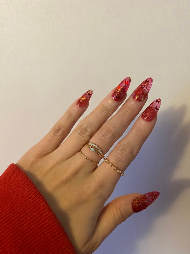 Bold Red Nail Design with Glitter, Floral Patterns, and Elegant Rings.