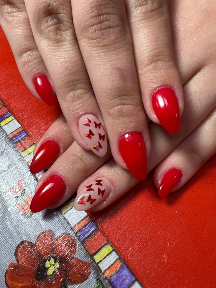 Bold Red Manicure with Glossy Finish and Whimsical Butterfly Accents for a Unique Look.