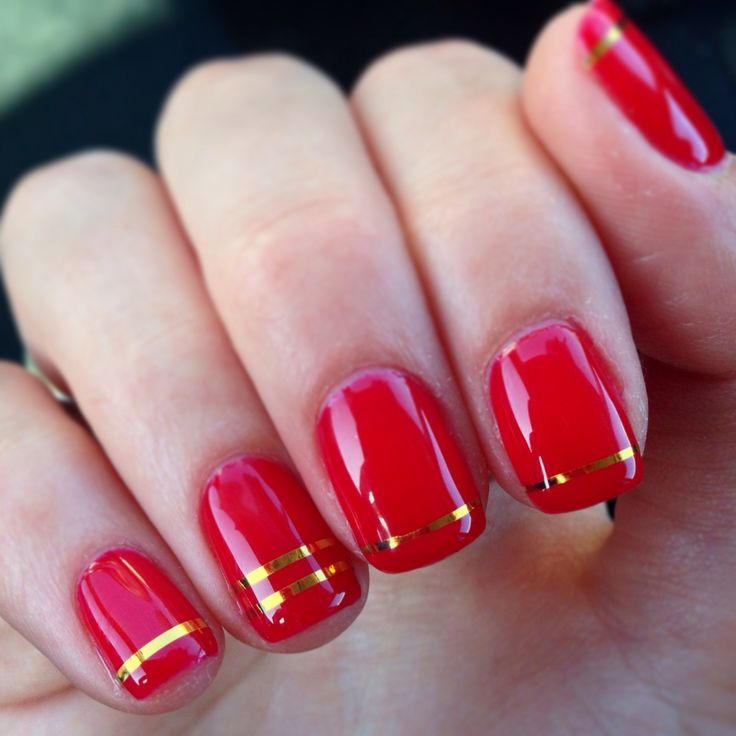 Chic Glossy Red Nails with Elegant Gold Accents for a Statement Look.