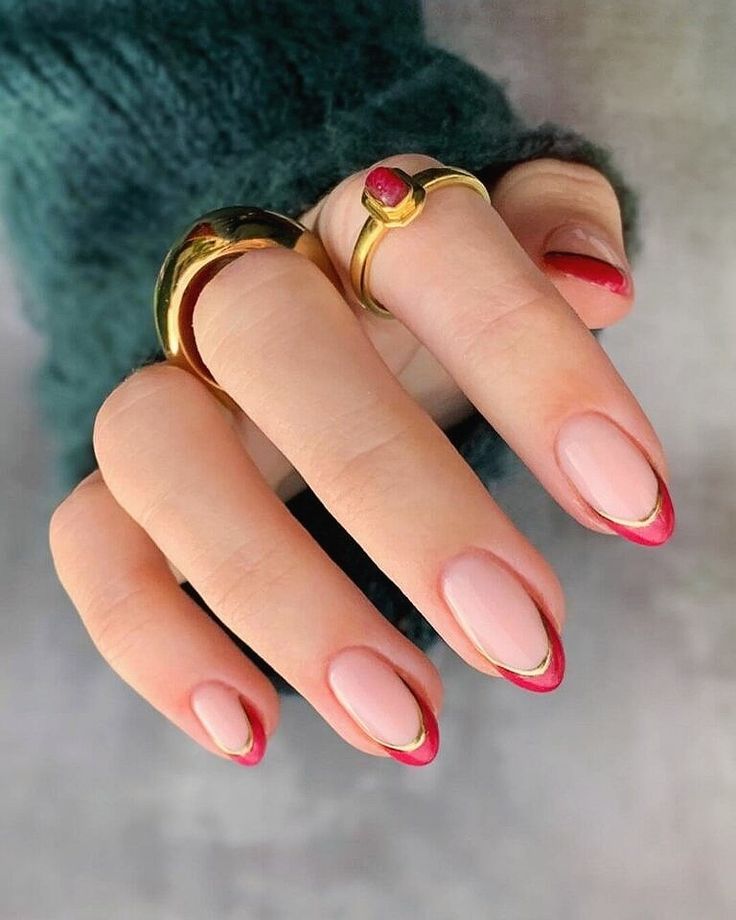 Chic Nail Design: Nude Base with Cherry-Red French Tips and Gold Accents.