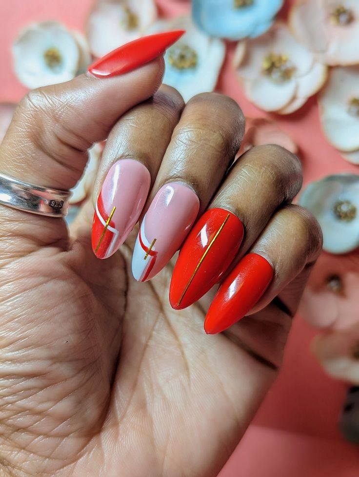 Elegant Red and Pink Nail Design with Pointed Tips and Gold Accents.