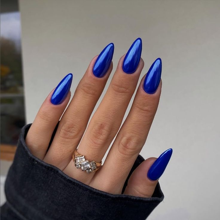 Elegant Cobalt Blue Almond-Shaped Nail Design with Shiny Finish and Delicate Ring Accent.