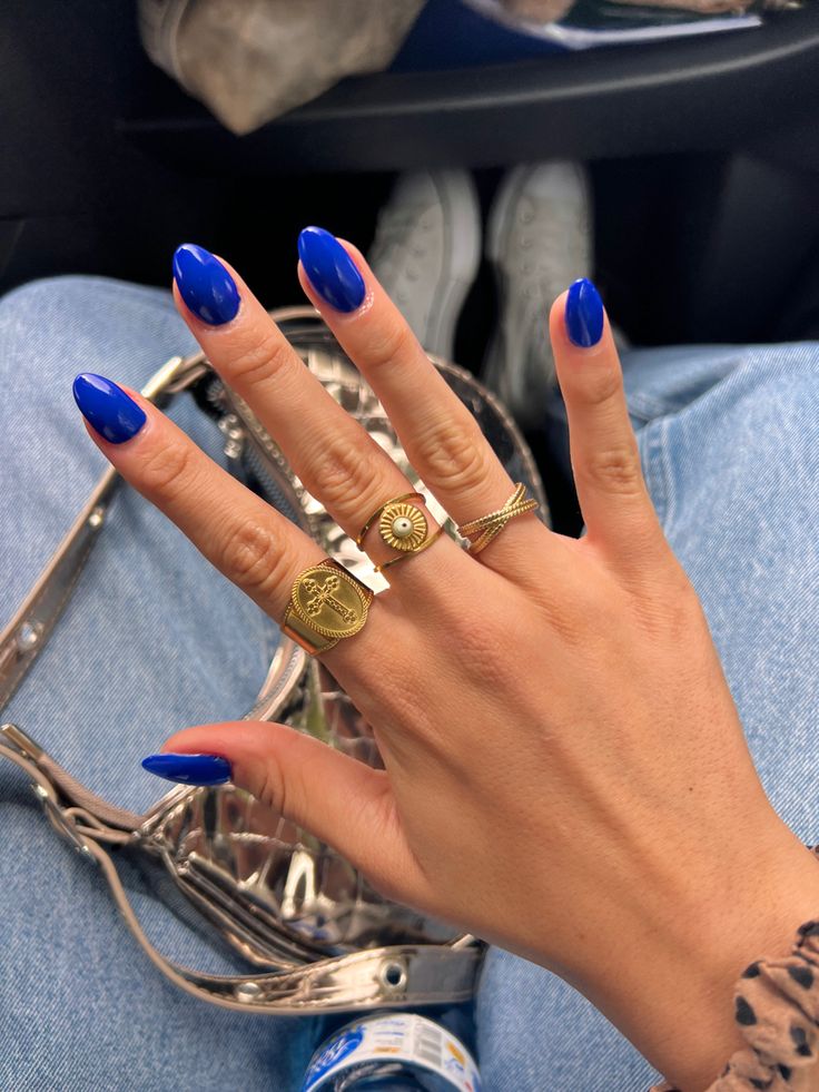 Stylish Vibrant Blue Nails Accentuated by Glossy Finish and Chic Gold Rings.