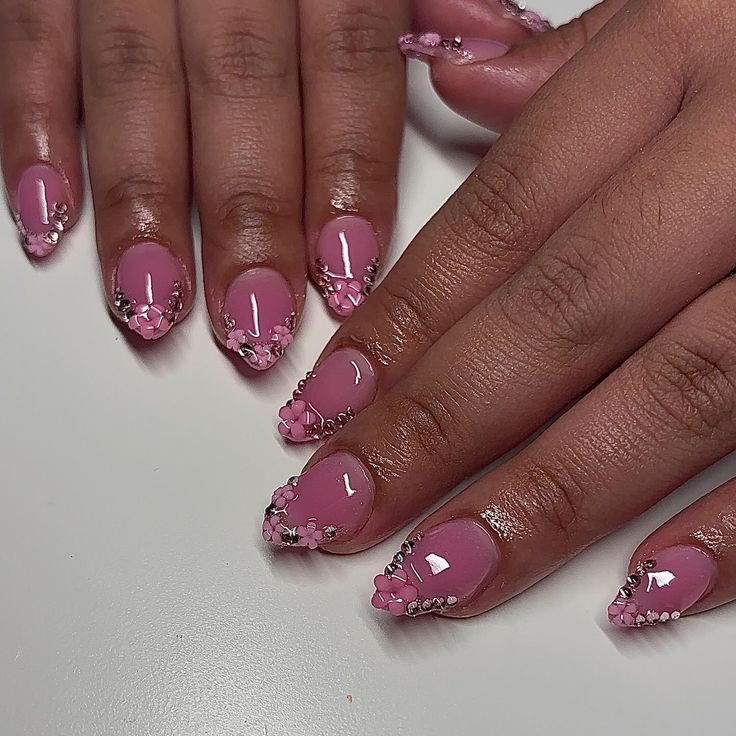 Sleek Pink Nails with Glossy Finish and Floral Gemstone Embellishments.