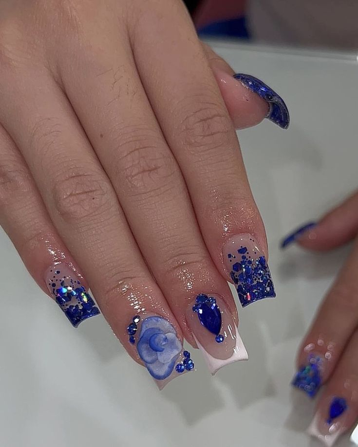 Elegant Blue Hued Nail Design with Glitter and Intricate Embellishments.