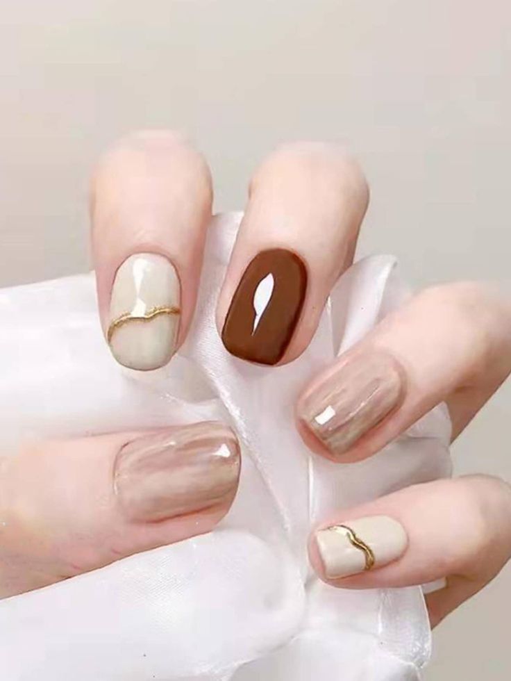 Elegant Neutral Nail Design with Glossy Finishes and Gold Accents