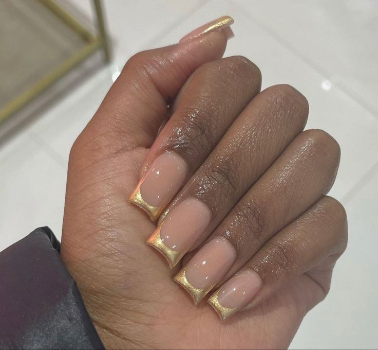 Sophisticated Glossy Nude Nail Design with Elegant Gold Triangle Tips.